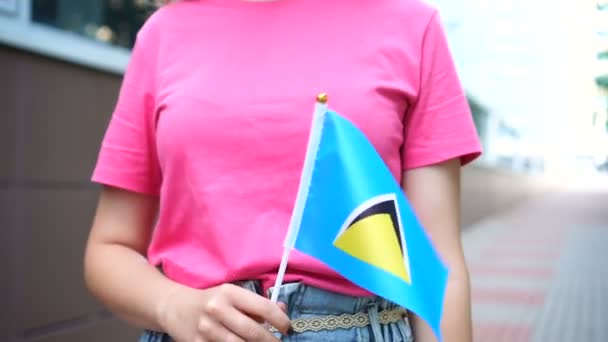 Mujer irreconocible sosteniendo la bandera de Santa Lucía. Chica caminando por la calle con la bandera nacional de Santa Lucía — Vídeo de stock