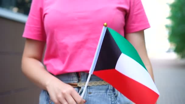 Oigenkännlig kvinna med kuwaitisk flagga. Flicka gå ner gatan med nationell flagga Kuwait — Stockvideo