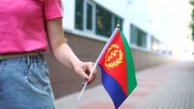 Eritre bayrağı tutan tanınmayan bir kadın. Ulusal Eritre bayrağıyla sokakta yürüyen bir kız