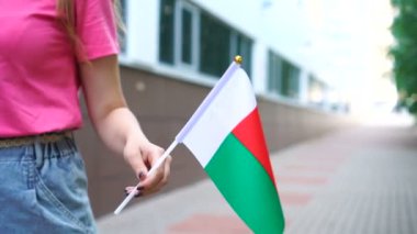 Elinde Malagasy bayrağı tutan tanınmayan bir kadın. Madagaskar 'ın ulusal bayrağıyla sokakta yürüyen bir kız