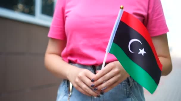 Unrecognizable woman holding Libyan flag. Girl walking down street with national flag of Libya — Stock Video