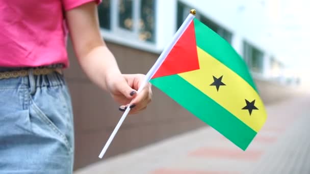 Неузнаваемая женщина с флагом Сан-Томеана. Девушка идет по улице с национальным флагом Сан-Томе и Принсипи — стоковое видео