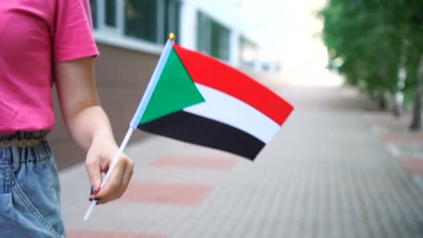 Mujer irreconocible con bandera sudanesa. Chica caminando por la calle con la bandera nacional de Sudán — Vídeos de Stock