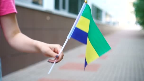 Eine unkenntliche Frau mit gabunischer Flagge. Mädchen läuft mit Nationalflagge Gabuns die Straße entlang — Stockvideo