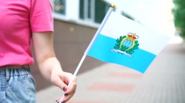 Sammarin bayrağı tutan tanınmayan bir kadın. San Marino bayrağıyla sokakta yürüyen bir kız.
