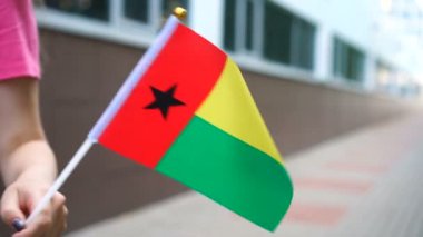 Elinde Bissau-Gine bayrağı tutan tanınmayan bir kadın. Ulusal Gine-Bissau bayrağıyla sokakta yürüyen bir kız.