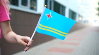 Aruban bayrağı tutan tanınmayan bir kadın. Aruba 'nın ulusal bayrağıyla sokakta yürüyen bir kız.