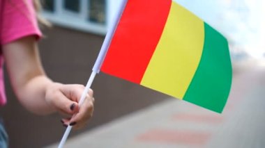 Elinde Gine bayrağı tutan tanınmayan bir kadın. Ulusal Gine bayrağıyla sokakta yürüyen bir kız