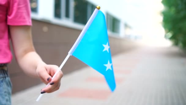ミクロネシア連邦の国旗を掲げている。ミクロネシア連邦国旗を手に街を歩く少女 — ストック動画