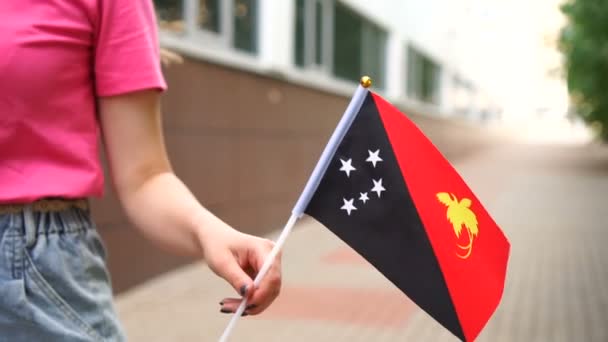 Mujer irreconocible sosteniendo la bandera de Papúa Nueva Guinea. Chica caminando por la calle con la bandera nacional de Papúa Nueva Guinea — Vídeos de Stock