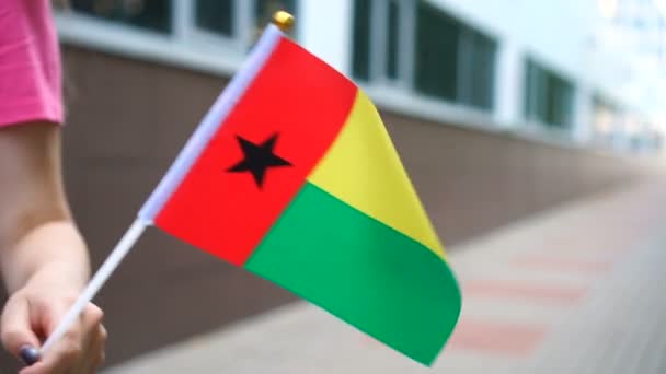 Eine bis zur Unkenntlichkeit verkleidete Frau mit der Flagge Bissau-Guineas. Mädchen läuft mit Nationalflagge von Guinea-Bissau die Straße entlang — Stockvideo