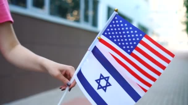 Oigenkännlig kvinna med amerikanska och israeliska flaggor. Flicka promenader ner gatan med nationella flaggor i USA och Israel — Stockvideo