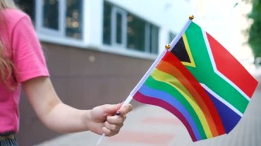 Ulusal Güney Afrika bayrağı ve Igbt gökkuşağı gay gurur bayrağını elinde tutan kadın.