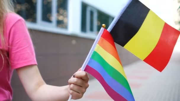 Жінка тримає національний німецький прапор і lgbt райдуга гей прапор в руках. — стокове відео