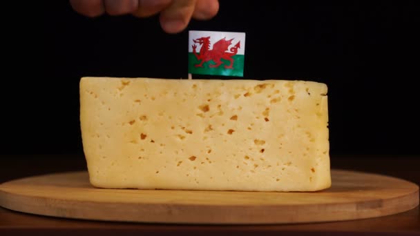Pánská ruka dát malé velikosti párátko s velšskou vlajkou na sýr. — Stock video
