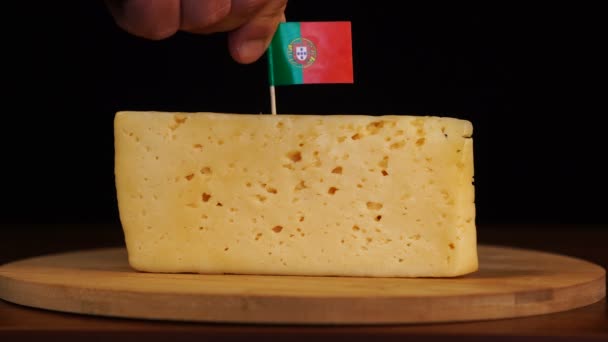 Mans mano poner pequeño en tamaño palillo de dientes con bandera portuguesa en el queso. — Vídeo de stock