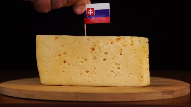 Mans mano poner pequeño en tamaño palillo de dientes con bandera eslovaca en el queso. — Vídeo de stock