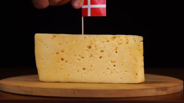 男の手はチーズにデンマーク語のフラグを持つサイズのつまようじに小さく置く. — ストック動画