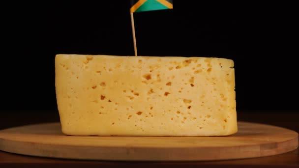 Mano de hombre poner pequeño en tamaño palillo con bandera jamaicana en el queso. — Vídeos de Stock