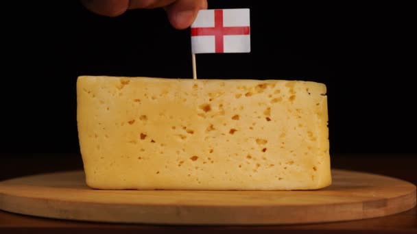 男の手はチーズに英語のフラグが付いているサイズのつまようじに小さく置く. — ストック動画