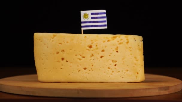 Mans hand gezet klein in grootte tandenstoker met uruguayan vlag op kaas. — Stockvideo