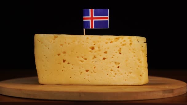 Mans Hand legt kleinen Zahnstocher mit isländischer Flagge auf Käse. — Stockvideo
