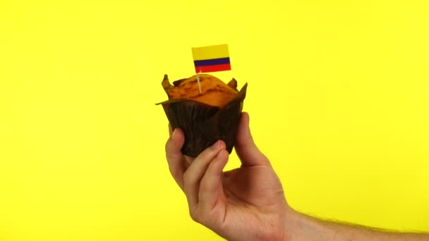 Dortík s kolumbijskou vlajkou na mužské dlani proti žlutému pozadí — Stock video