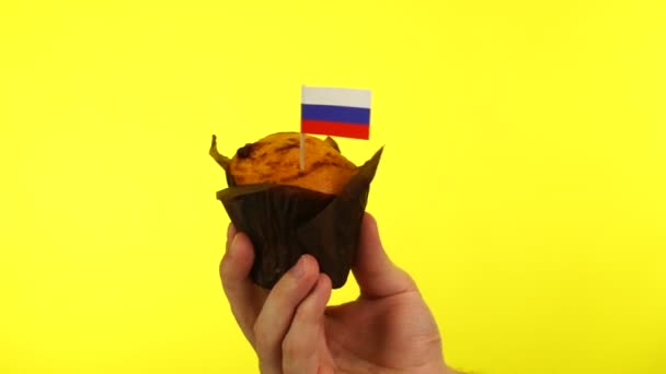 黄色の背景を持つ男性の手のひらにロシア語のフラグを持つカップケーキ — ストック動画