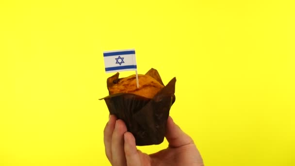 Babeczka z flagą Izraela na męskiej dłoni na żółtym tle — Wideo stockowe
