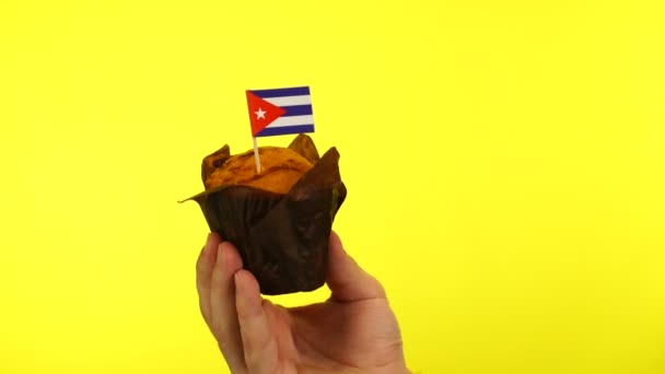 Cupcake met Cubaanse vlag op mannelijke palm tegen gele achtergrond — Stockvideo