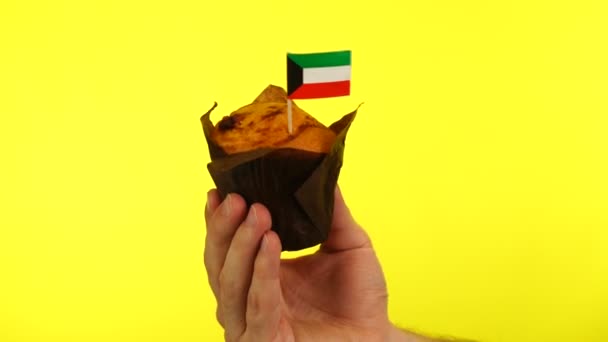 Кекс с кувейтским флагом на мужской ладони на желтом фоне — стоковое видео