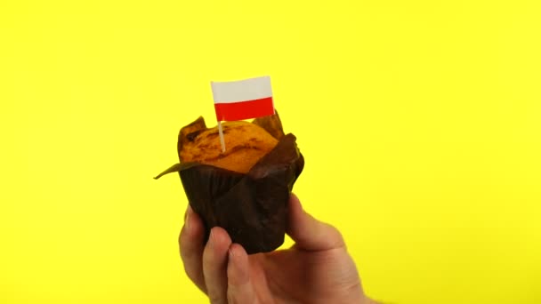 Cupcake mit polnischer Flagge auf männlicher Handfläche vor gelbem Hintergrund — Stockvideo