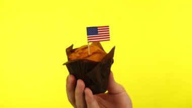 Sarı arka planda erkek avucunda Amerikan bayrağı olan kek.