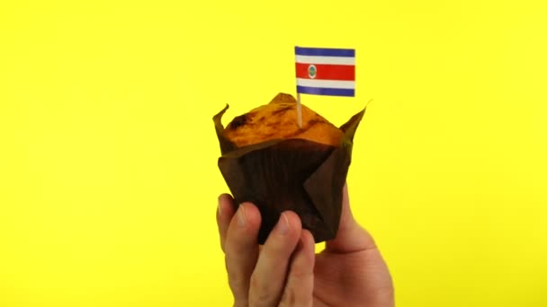 Cupcake com bandeira norte-coreana na palma da mão masculina contra fundo amarelo — Vídeo de Stock