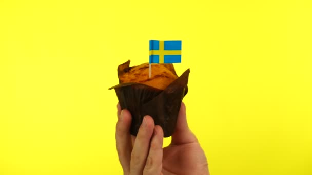 Cupcake con bandera sueca sobre palma masculina sobre fondo amarillo — Vídeos de Stock