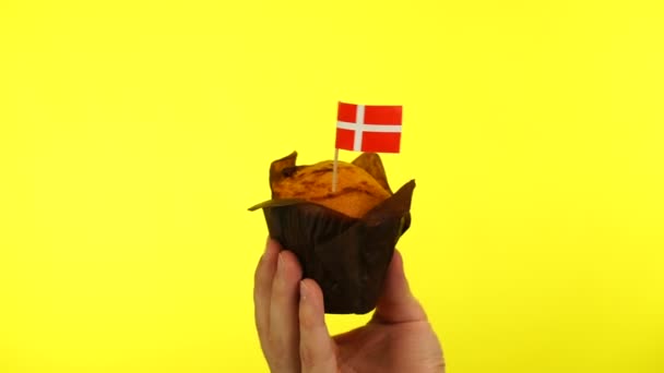 Cupcake com bandeira dinamarquesa na palma do macho contra fundo amarelo — Vídeo de Stock