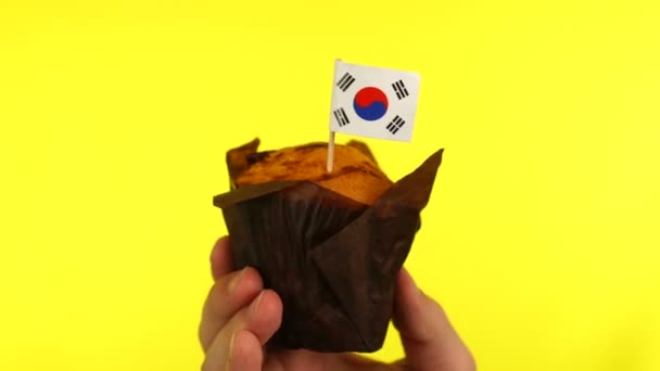 Cupcake with South Korean flag on male palm against yellow background — Stock Video