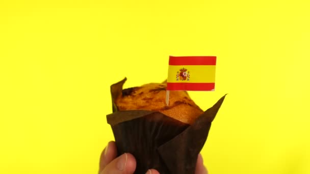 Cupcake with Spanish flag on male palm against yellow background — Stock Video