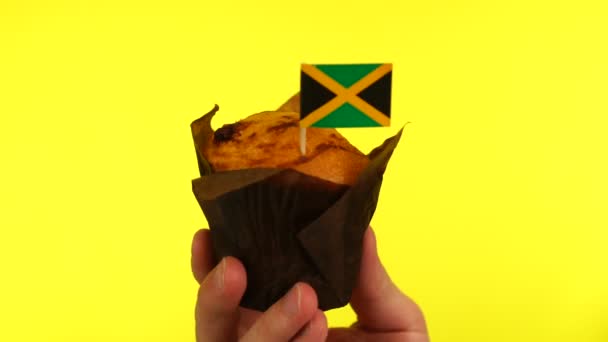 Cupcake med jamaicanska flagga på manliga handflatan mot gul bakgrund — Stockvideo