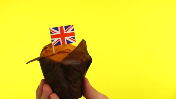 Cupcake com bandeira de macaco da União na palma do macho contra fundo amarelo — Vídeo de Stock