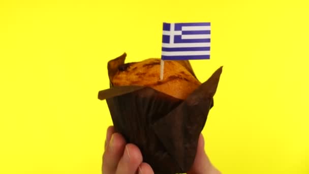 Cupcake with Greek flag on male palm against yellow background — Stock Video