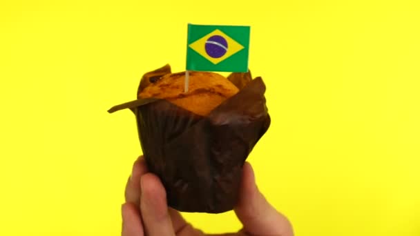 Торт з бразильським прапором на чоловічій долоні на жовтому тлі. — стокове відео