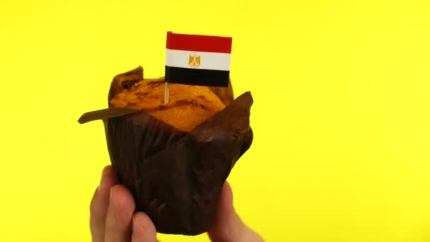 Cupcake with Egyptian flag on male palm against yellow background — Stock Video