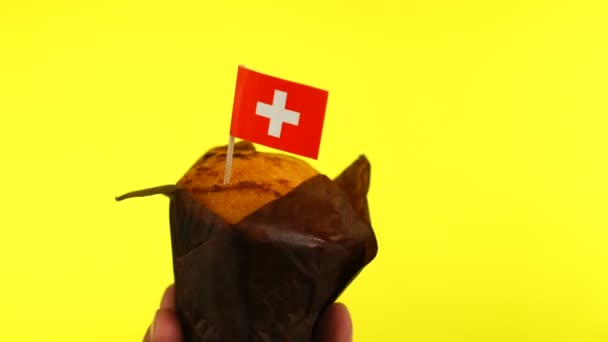 Cupcake met Zwitserse vlag op mannelijke palm tegen gele achtergrond — Stockvideo