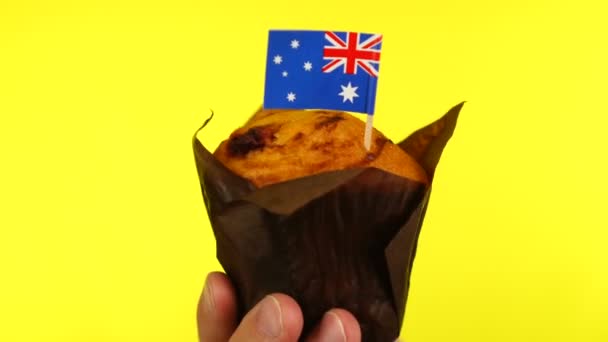 Кекс с австралийским флагом на мужской ладони на желтом фоне — стоковое видео
