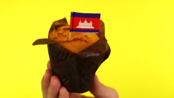 Cupcake mit kambodschanischer Flagge auf männlicher Palme vor gelbem Hintergrund — Stockvideo