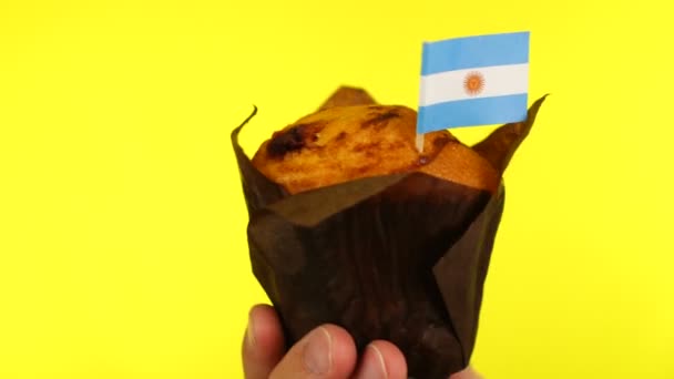 Cupcake met Argentijnse vlag op mannelijke palm tegen gele achtergrond — Stockvideo