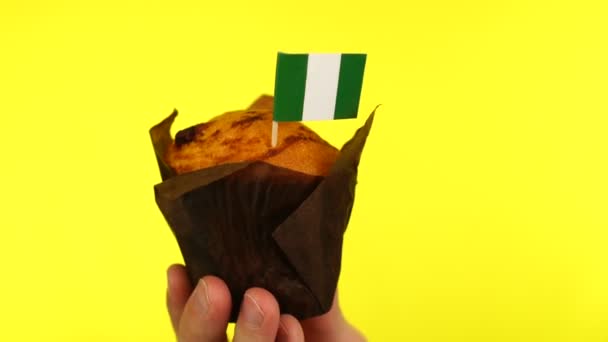 Кекс с нигерийским флагом на мужской ладони на желтом фоне — стоковое видео