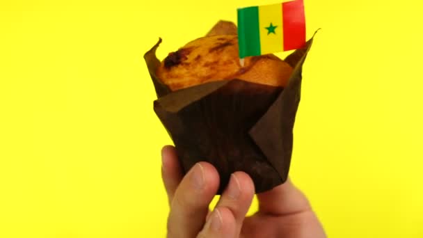 Cupcake met Senegalese vlag op mannelijke palm tegen gele achtergrond — Stockvideo