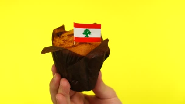 Cupcake with Lebanese flag on male palm against yellow background — Stock Video